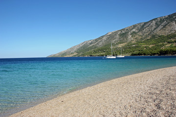 Beach with blue sea water and parked yachts