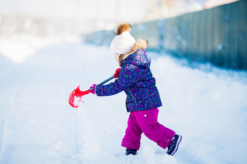 Fototapeta na wymiar Little girl with a snow shovel.