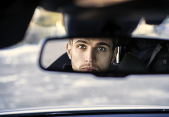 Handsome Blond Young Man Driving a Car, Wearing Black Sweater. hand on wheel