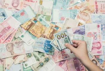 Female hand holding american hundred dollar bills over Asia money background.  World Markets and Trade.