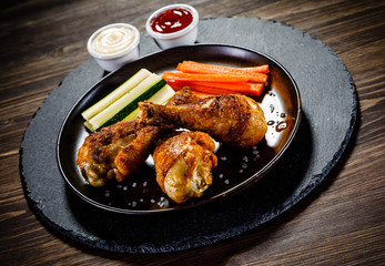 Roast chicken drumsticks on wooden background