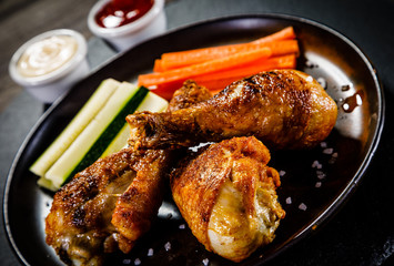 Roast chicken drumsticks on wooden background