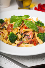 A delicious fresh gourmet Italian strozzapreti pasta dish, with pancetta, italian sausage, broccoli, vegetables, topped with fresh basil.