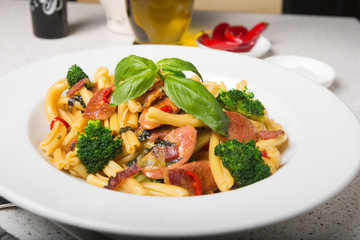 A delicious fresh gourmet Italian strozzapreti pasta dish, with pancetta, italian sausage, broccoli, vegetables, topped with fresh basil.