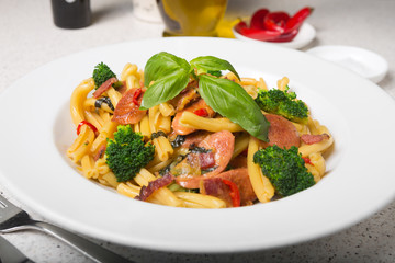 A delicious fresh gourmet Italian strozzapreti pasta dish, with pancetta, italian sausage, broccoli, vegetables, topped with fresh basil.