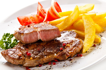 Grilled steaks, French fries and vegetables