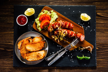 Grilled sausages with toasts on wooden table