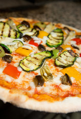 Close up of a Vegetarian thin crust  pizza, with grilled courgette, peppers, aubergine, artichoke, cheese and tomato topping