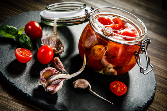 Tomatoes in jar on wooden background