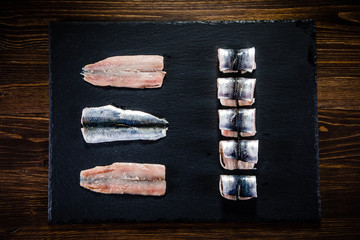 Raw herring on black stone