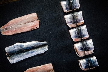 Raw herring on black stone