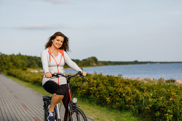 Fototapeta na wymiar Young woman riding bike at seaside