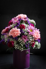 Still life Bouquet of  various flowers in a vase against dark moody background, selective focus