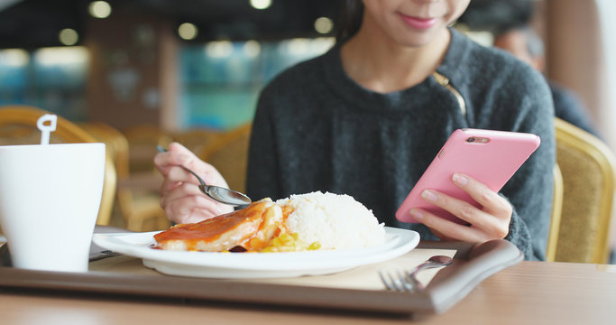 Busy Woman Having Lunch In Restaurant With Using Mobile Phone