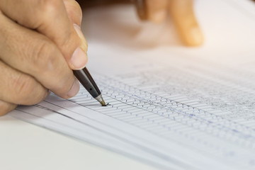 Hand Businessman holding pen for writing checking reports papers over application form.