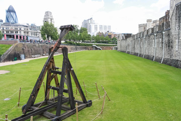 ancient catapult standing at the bottom of the ditch near the wall of the tower of London