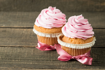 Closeup of cupcakes with vanilla, berries, pink and white cream, chocolate and sprinkles on wooden background. Selective focus. Sweet dessert tasty food concept muffin.
