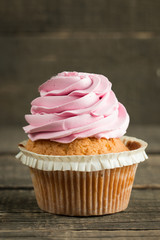 Closeup of cupcakes with vanilla, berries, pink and white cream, chocolate and sprinkles on wooden background. Selective focus. Sweet dessert tasty food concept muffin.