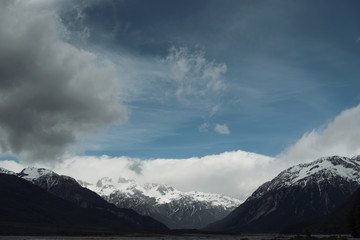 Paisaje de montañas nevadas con cielo azul nuboso.