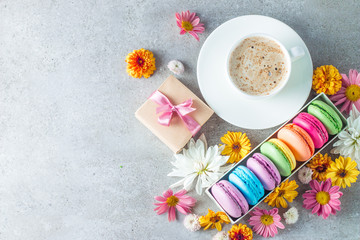 Photo of cake macarons, gift box, tea, coffee, cappuccino and flowers. Sweet romantic food macaroon concept. Morning breakfast and presents.