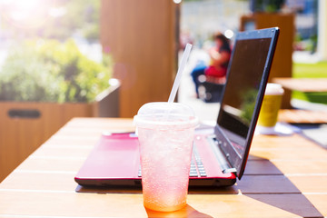 Red laptop and refreshing summer cocktail on a wooden table