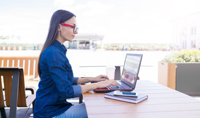 Work in a cafe in the fresh air. Attractive young woman working behind laptop outdoors