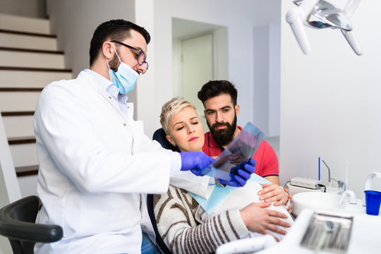 Attractive bearded man with his pregnant wife having medical treatment in dental office