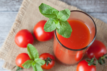 Close-up of a glass of tomato juice with vegetables on wooden sacking background. Vitamins and minerals. Healthy drink concept.