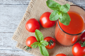 Close-up of a glass of tomato juice with vegetables on wooden sacking background. Vitamins and minerals. Healthy drink concept.