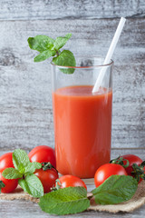 Close-up of a glass of tomato juice with vegetables on wooden sacking background. Vitamins and minerals. Healthy drink concept.