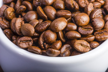 coffee beans in a white cup on a dark wood background