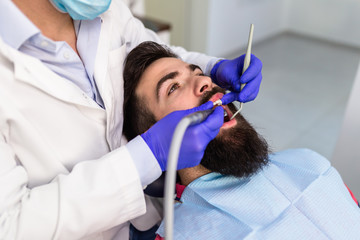 Young attractive bearded man receiving dental treatment