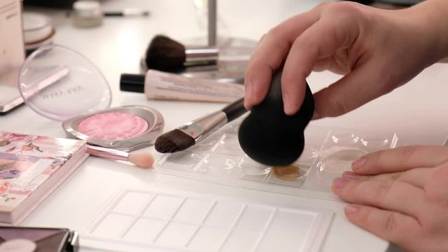 Make-up artist using sponge to apply pressed powder