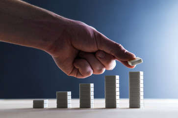 Progress, planning strategy, rise in sales or success in business concept. Future prediction and estimation with high expectations. Development and improvement. Growing graph. Hand stacking tiles.
