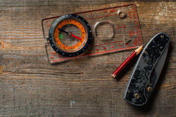 Wood background with compass,   pencil and  pocket knife.