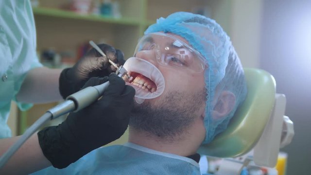 Doctor and patient with lip dilator in the dental office, polishing with brush