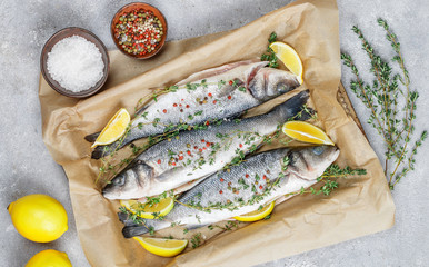 Fresh raw fish (seabass) is ready for baking with lemon, thyme, sea salt and pink pepper. Prepare a gourmet dinner. Selective focus
