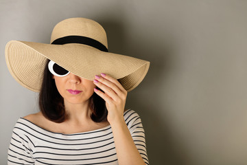Woman in a white striped top, hat and white sunglasses.