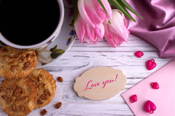 Valentines day greeting card with pink tulips coffe cup cookies and lettering Love you.