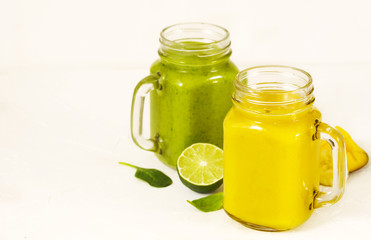 Green Spinach Avocado Smoothie and Banana Mango Smoothie in mason jars. Healthy vegan eating.