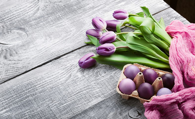 luxurious fresh fashionable purple tulips on a wooden background next to Easter eggs