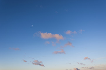 Sunrise sky with orange/purple clouds and the moon in the distance