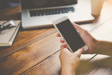 businessman working on smart phone and laptop in open space office. Meeting report in progress.