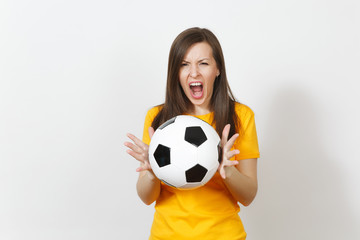 Beautiful European young angry screaming woman, football fan or player in yellow uniform holding soccer ball isolated on white background. Sport, play football, health, healthy lifestyle concept.