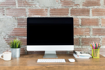 workspace with computer with blank black screen, and office supplies on a wooden desk