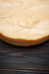 Whole round Head of parmesan or parmigiano hard cheese on wooden background