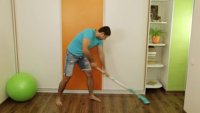 Tired man washes the floor with a mop. March 8, Women's Day.