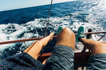 Young woman in colorful dotted dress with ballerinas and man in shorts with turquoise shoes sitting...