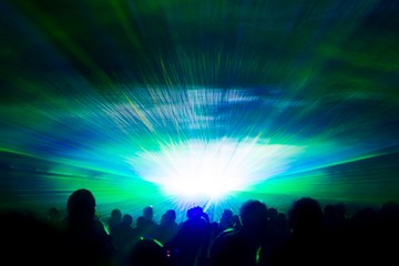 Colorful laser show nightlife hypnosis light tunnel people crowd. Luxury entertainment with audience silhouettes in nightclub event, festival or New Year's Eve. Beams and rays shining colorful lights