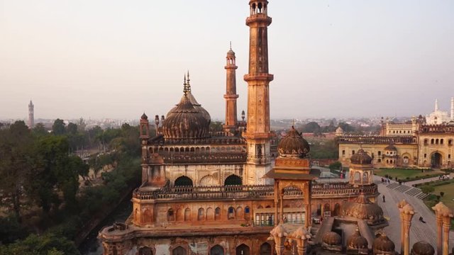 Aerial panning shot of the bara imambara and asif mosque in lucknow india. Shot at sunset it showcases the beautiful mughal architecture of the building and the lush lawns surrounding it. Shot from